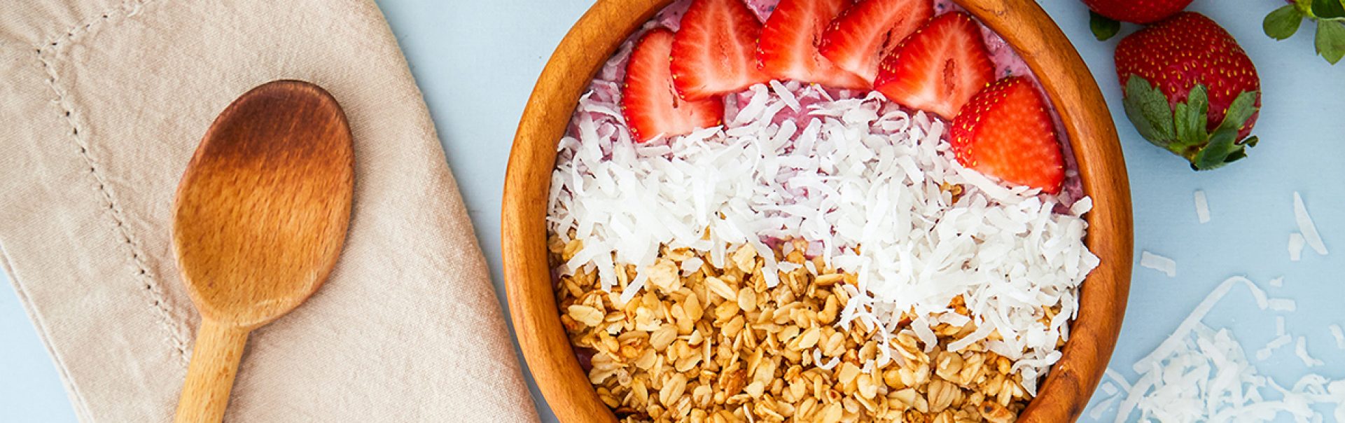 A bowl of strawberries, coconut and grains.