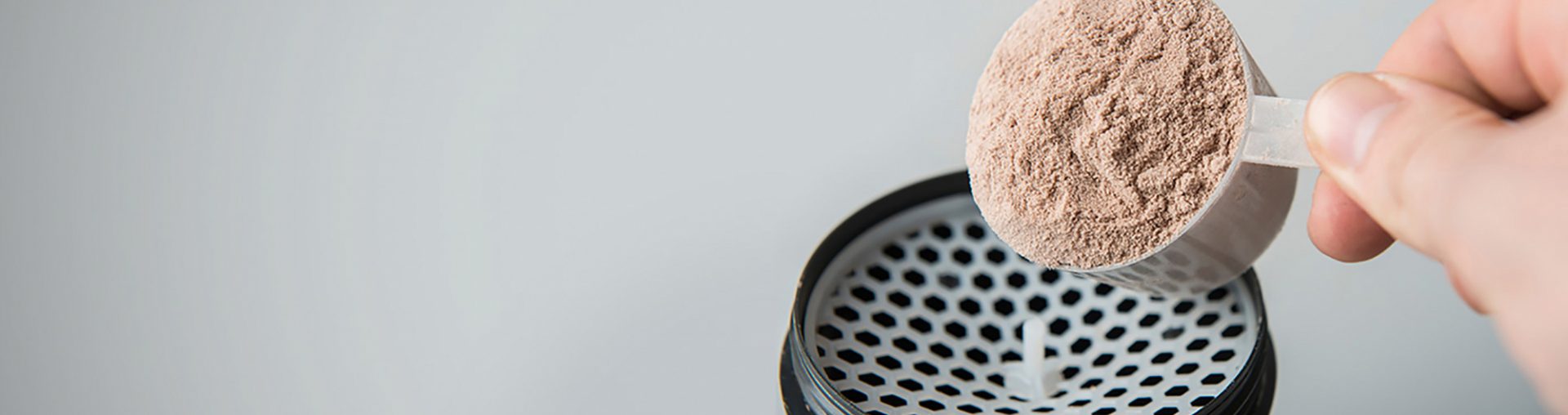Protein powder being poured into a blender.