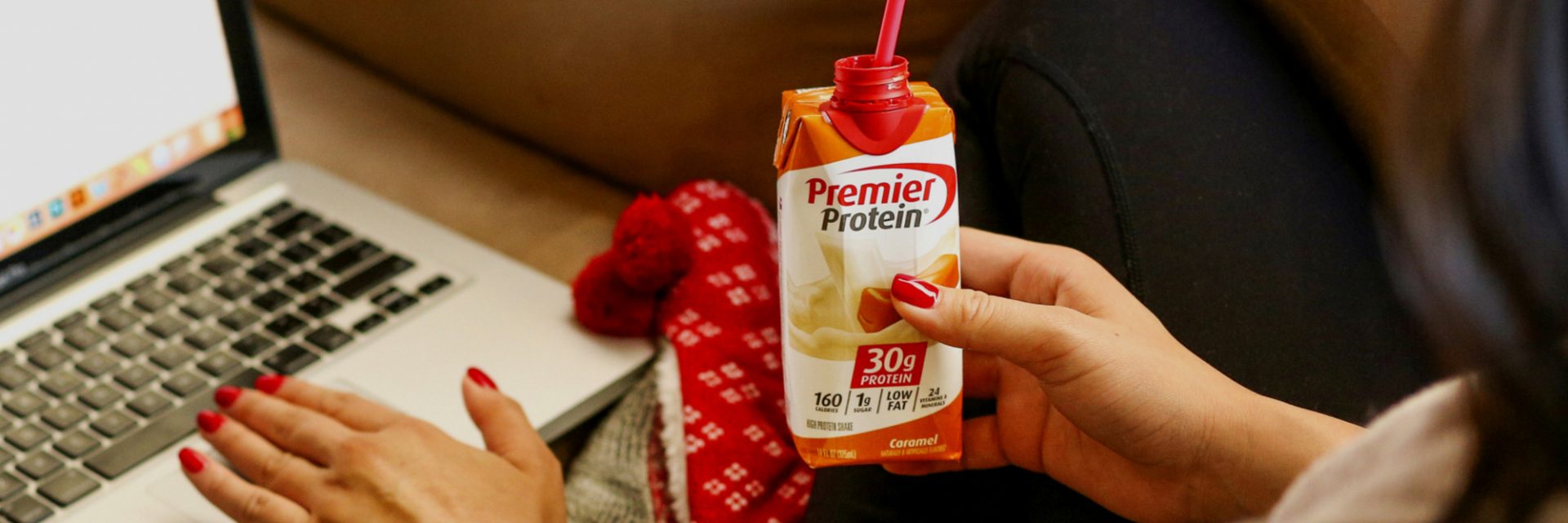 A women at a computer drink a Premier Protein Caramel Protein Shake