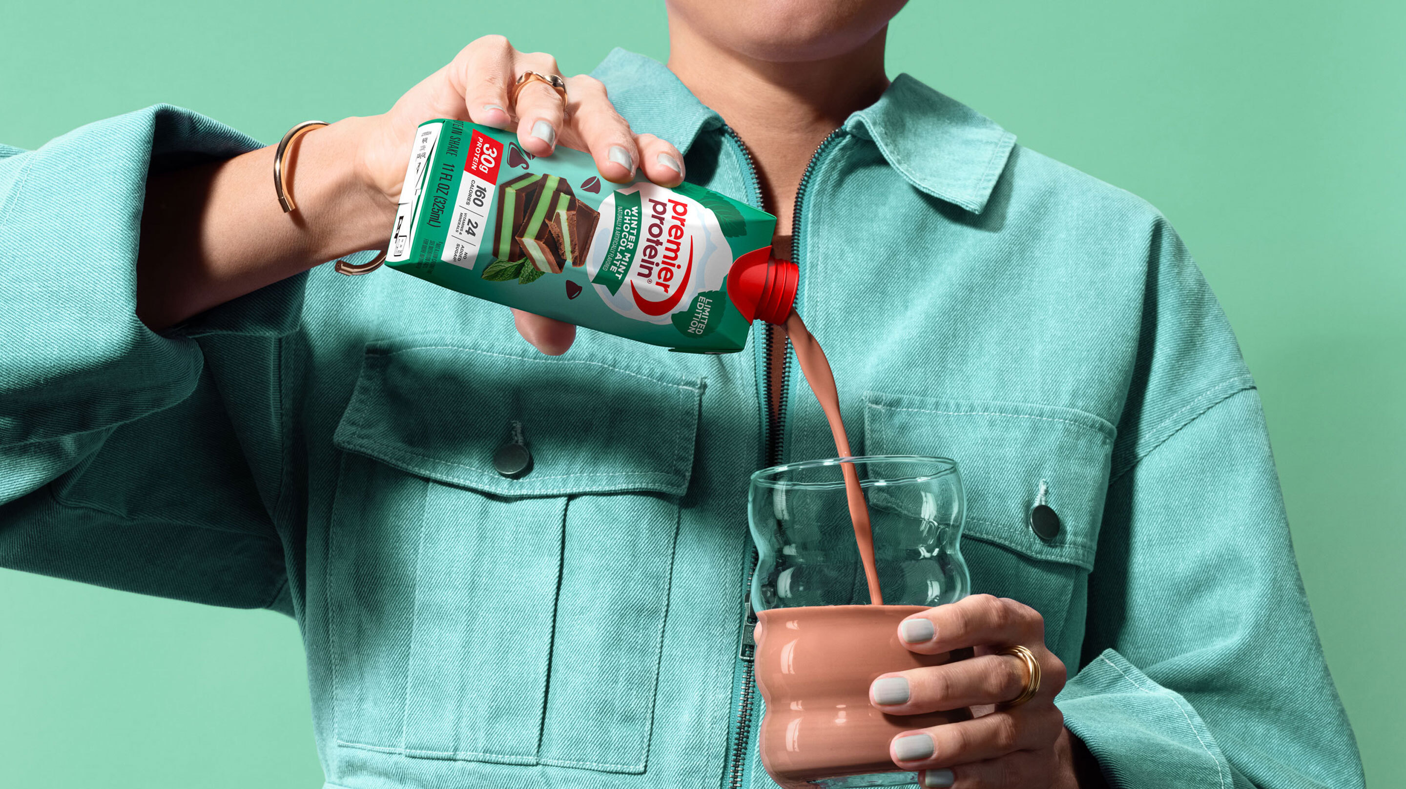 A person pouring a Premier Protein Winter Mint Chocolate Protein Shake into a glass.